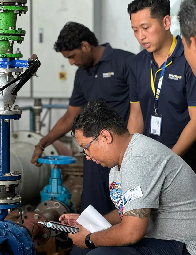 a group of men looking at an engineering pipe with pump system